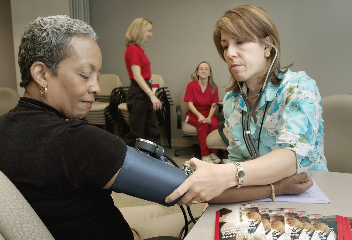 A caregiver checking the blood pressure of an older South Asian woman at home