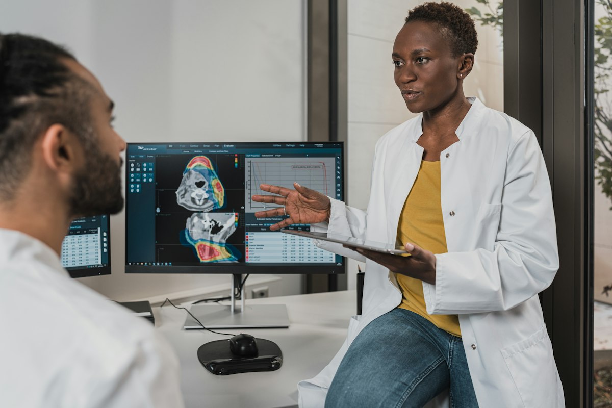 Clinicians reviewing a patient’s medical scans and health data on screen